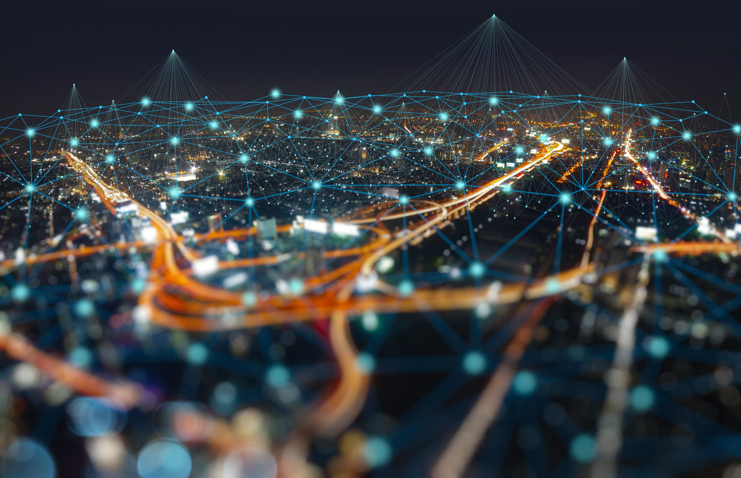Aerial night view of city highways with digital network connections representing smart infrastructure and data flow