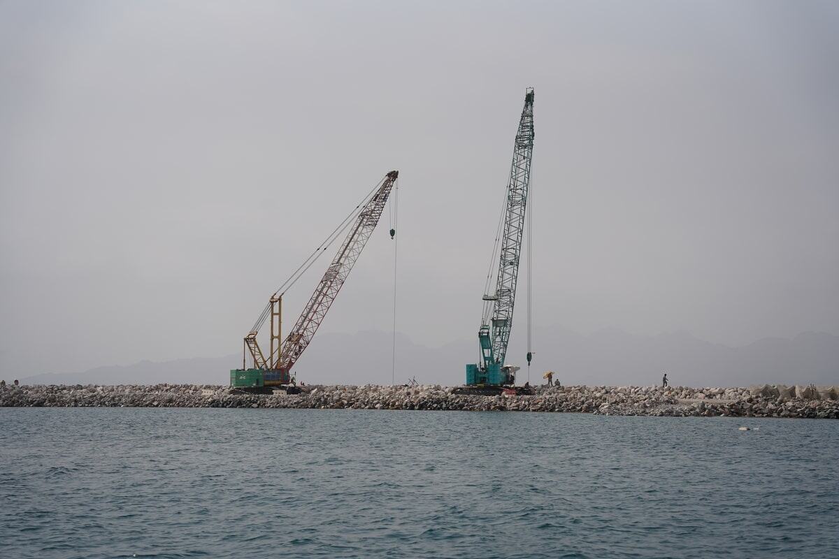 A pair of KOBELCO hydraulic crawler cranes helping reinforce marine barriers on a construction site in Oman