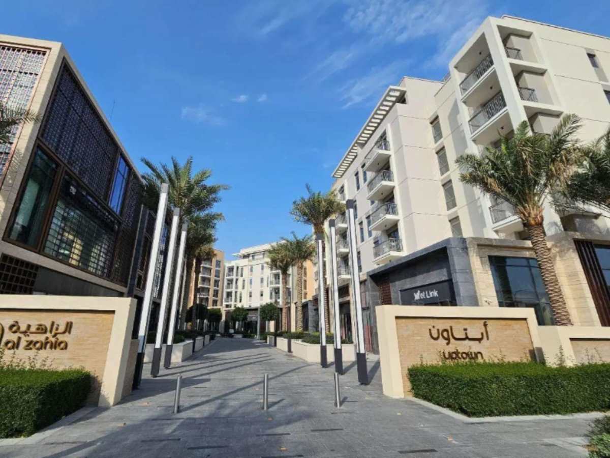 Contemporary residential buildings with palm-lined walkway and gated entrance in urban community