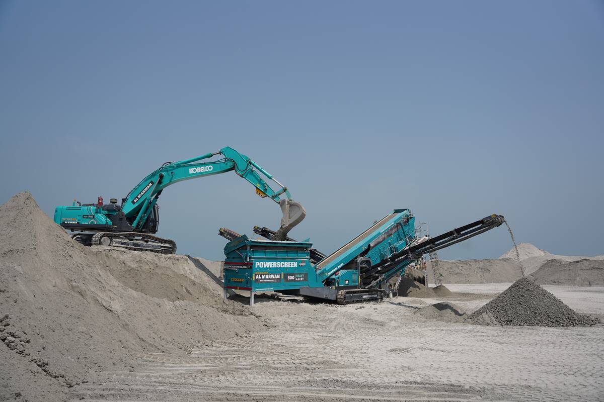 A Kobelco excavator feeding debris into the screener bar hopper